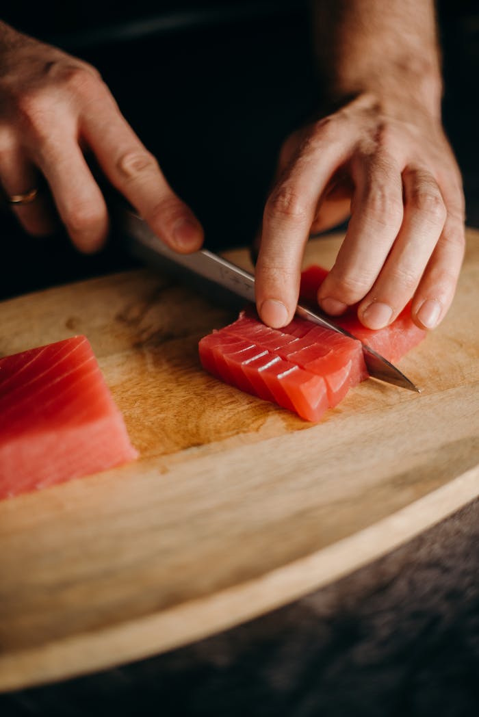 Crafting Captivating Headlines: Your awesome post title goes here Close-up of hands slicing fresh tuna on a wooden cutting board, perfect for Asian cuisine themes.
