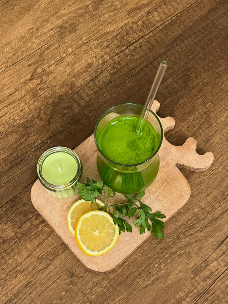 A vibrant green drink on a wooden board with fresh citrus slices and parsley for a healthy lifestyle.